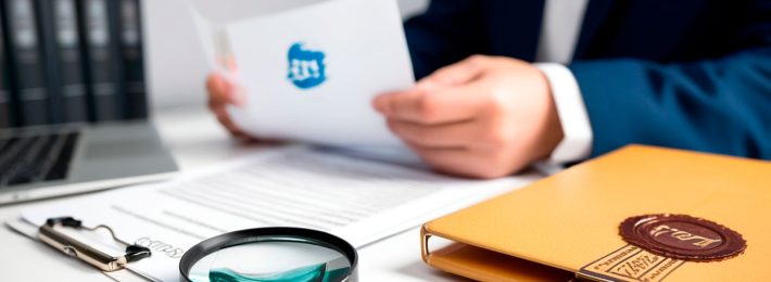 Profesional revisando documentación de registro de marca con lupa y sello oficial